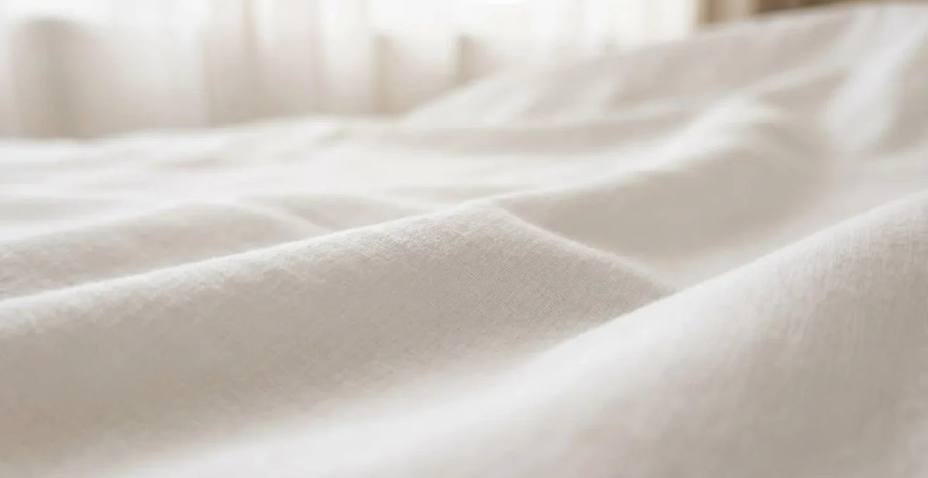 Détail macro d'un tissu de linge hospitalier blanc texturé évoquant le repos et la sérénité